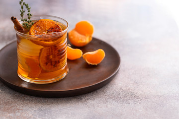 Whiskey sour cocktail with tangerine slices and ice cubes decorated with cinnamon and thyme. Alcohol drink background.