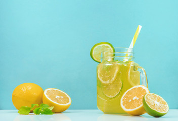 Lemonade drink of soda water, citrus and mint on the light blue background. Cocktail glass with...