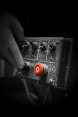 Man pressing button on an industrial machine control panel. With lighting effect and selective colour