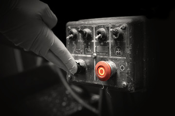Man pressing button on an industrial machine control panel. With lighting effect and selective...