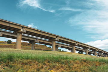 Fototapeta na wymiar Road highway bridge, viaduct supports in the valley among the green hills, transport infrastructure.