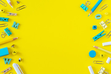 Multicolored school supplies on yellow background with copy space.