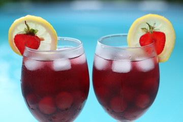 Alcoholic cocktail with lemon and strawberry on the side of the pool