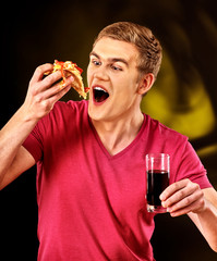 Man eat fast food pizza piece and drink glass of cola with good appetite.
