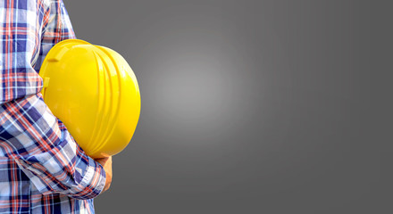 Concept construction worker on Gray background,construction worker holding safety yellow helmet with for the safety of the work operation,copy-space