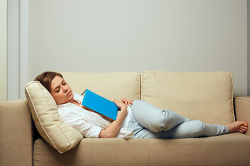 Woman lying on sofa sleep with open book