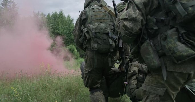 Soldiers evacuated the wounded soldier in a stretcher, a rescue operation under cover, smokescreen on field, 4k slow motion.