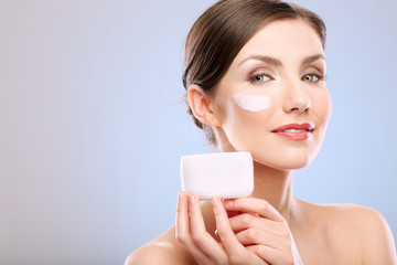 Beauty portrait of woman with clean skin holding cream jar.