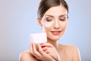 Close up beauty face portrait of young woman with cream jar.