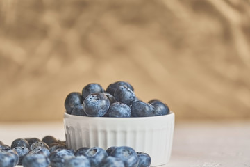 close up of bowl with blueberries on golden background