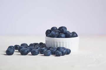 close up of bowl with blueberries on white concrete background