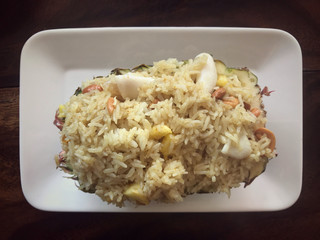 Food - Thai pineapple seafood fried rice served in a white plate.