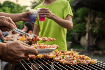 BBQ party group of people at barbecue dinner friends having food together outdoor as summer with...