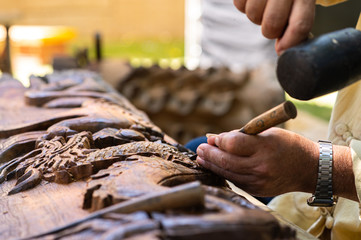 Closeup hands of local craftman carve with gogue tool and create an amazing Thai Northern handcraft...