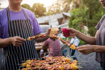 BBQ party group of people at barbecue dinner friends having food together outdoor as summer with friendship asian person.