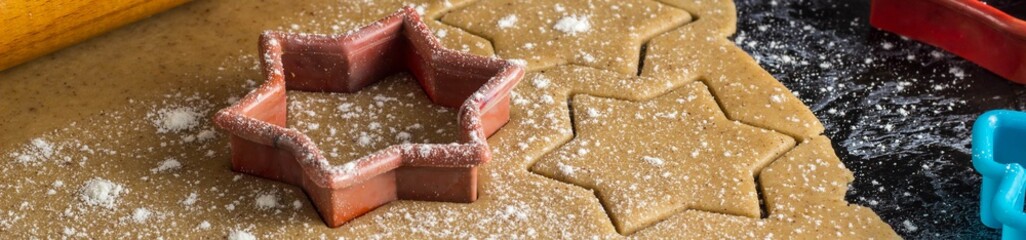 Banner of Cooking Christmas gingerbread cookies with rolling pin on a dark background