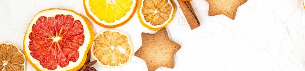Border of Dried slices of various citrus fruits gingerbread and spices on white background with copyspace