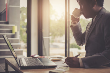 A young business man is sipping coffee while working.
