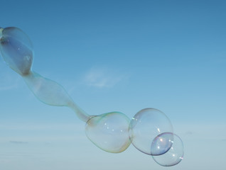Large, soap bubbles against the blue sky. Lake Ladoga, sunny day.