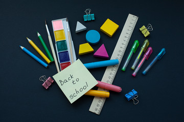 Back to school. notebooks, pens, pencils, paint on a black background, top view. Concept of education.