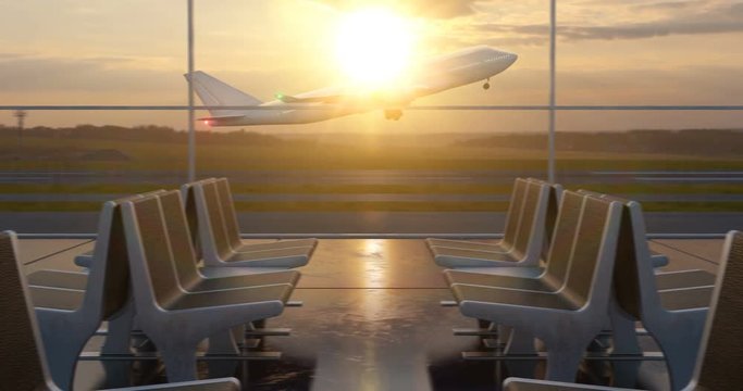 Large passenger airplane taking off the runway as seen from airport departure hall windows with sunset sky on background.