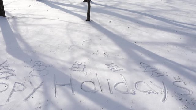 Inscription of happy holidays on snow. Shooting in the winter.