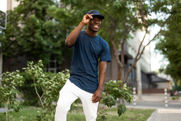 African american man in empty t-shirt and cap standing in summer city street