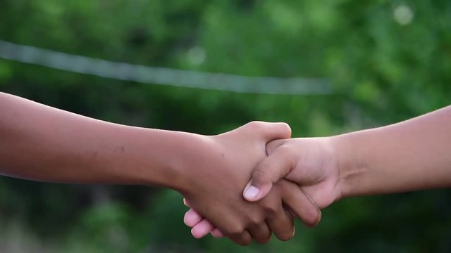 Closeup of two little child hands shaking in agreement.Children shaking hands,the concept of mutual assistance and friendship