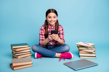 Portrait of her she nice attractive sweet lovely cheerful cheery girl in checked shirt sitting in lotus pose using app device isolated over bright vivid shine blue green background