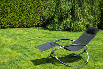 Rocking lounger on a green grass. Summer time. Copy space