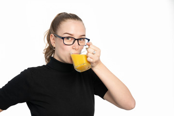 studio shot of a young woman hold a glass of orange juice and drinks