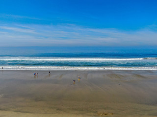 Aerial view people enjoying the beach during sunny day. Huntington Beach, Southeast Los Angeles, California. USA