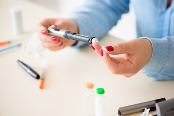 Woman taking blood sample with lancet pen. Diabetes.