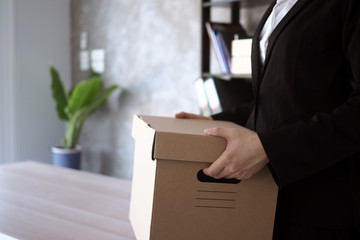 Businesswoman hold boxes for personal belongings and resignation letters.