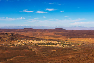 Fototapeta na wymiar View over a village in Morocco with snowy Atlas mountains in the background