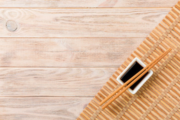 Bamboo mat and soy sauce with sushi chopsticks on wooden table. Top view with copy space background for sushi. Flat lay