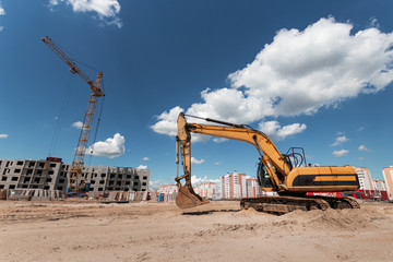 Excavator at a construction site against the background of a tower crane. Construction, technology