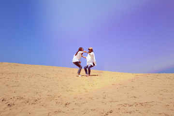 砂漠で手を取り合って立ち上がる女子