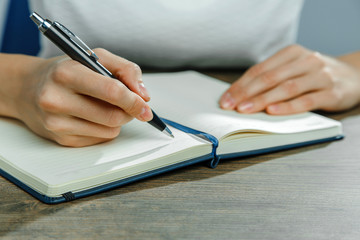 Female hands are writing in a notebook