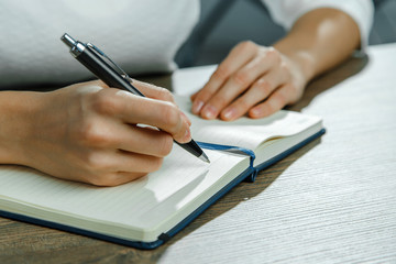 Female hands are writing in a notebook