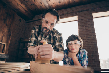 Close up photo focused interested inspired people person dad daddy child masterclass support explain show occupation bearded master plaid trendy stylish indoors home garage glasses goggles protective