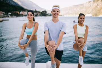 Group of happy people exercising outdoor. Sport, fitness, friendship and healthy lifestyle concept