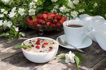 Granola with oatmeal milk with strawberries for breakfast in the summer garden. Morning at the cottage. Cup of coffee.