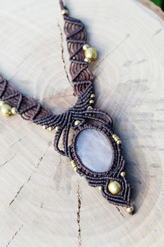 Macrame necklace with natural mineral gemstone on wooden background