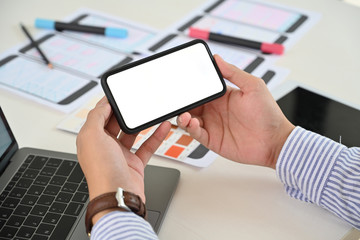 Businessman hand holding blank screen mobile phone on desk workspace.