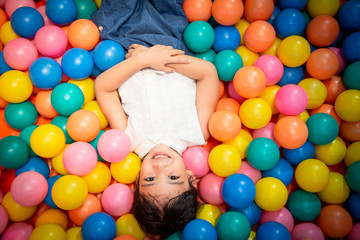 Fototapeta na wymiar Happy asian girl playing in colorful balls pool
