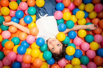 Fototapeta na wymiar Happy asian girl playing in colorful balls pool