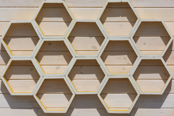 A honeycomb pattern made of wooden planks illuminated by bright outdoor light.