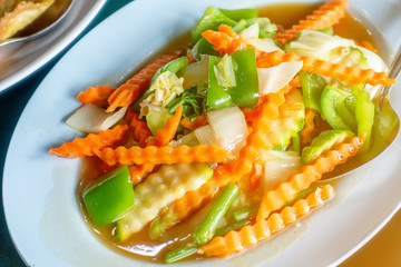 The dish of mixed fried vegetables such as carrot cucumber bell pepper with oil.