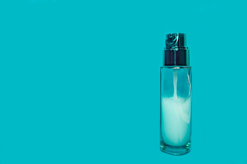 glass bottle with cosmetic serum dispenser on a blue background close-up